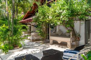 a patio with a bed and chairs and trees at Ocean Star Villa Five near the KuDeTa Beach in Seminyak