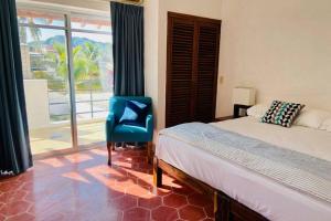 sypialnia z łóżkiem, niebieskim krzesłem i oknem w obiekcie Casa Piramide: Fully Furnished 2-Bedroom House w/ Private Swimming Pool and Waterfall, 5 Minute Walk from the Beach w mieście Barra de Navidad