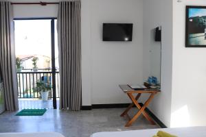 a living room with a table and a tv on a wall at Green garden house in Hoi An