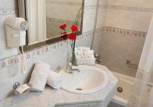 a bathroom with a sink and a vase of red flowers at Hotel Impala in Buenos Aires