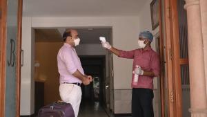 two men wearing face masks standing in a hallway at Hotel Bhakti Dhama in Vrindāvan