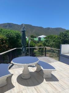 a table with a closed umbrella on a patio at Hemel-en-See Beach House in Hermanus