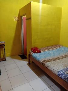Pokój z łóżkiem i żółtą ścianą w obiekcie Penginapan Dinafizka w mieście Bogor