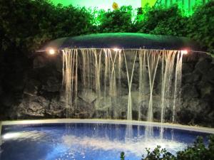 una cascada en una piscina por la noche con luces en Hotel Colonial, en Teziutlán