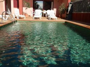 a swimming pool with chairs and a table and water at Casa Bonita in Riumar