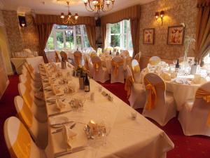a banquet room with white tables and chairs with white table linen at Woodlands Hotel in Spalding