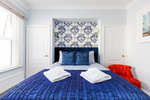 Ashbys Accommodation & Spa hire في بورتسماوث: غرفة نوم بسرير ازرق وفوط بيضاء
