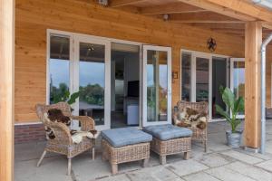 a porch with wicker chairs and a ottoman at Ride by the Sea Guesthouse in Koudekerke +16 photos