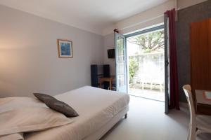 1 dormitorio con 1 cama y puerta corredera de cristal en Le Pavillon Bleu Hotel Restaurant en Royan