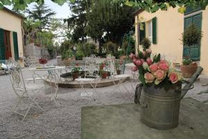a bucket of flowers in a yard with chairs and tables at Residenza Dei Ricci in Chiusi