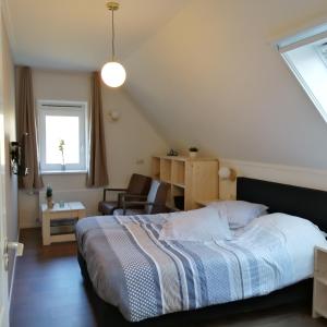 a bedroom with a bed and a chair and a window at Veenemaat in Winterswijk