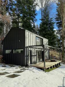 ein schwarzes Haus mit einer Terrasse im Schnee in der Unterkunft Minimal House in Szczyrk