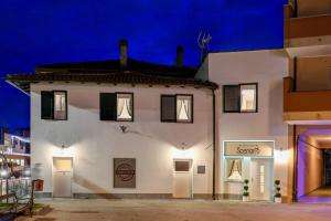 a white building with black shuttered windows at night at Affittacamere Scenario in Fogliano Redipúglia