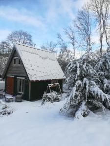 una pequeña casa con nieve en el techo en WillowTree Cottage en Avèze