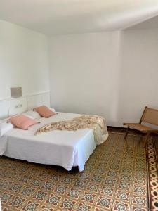 een slaapkamer met een groot wit bed en een stoel bij Ecoturisme Mas Ribas in Palamós