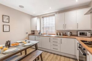 a kitchen with white cabinets and a table at Great Gate House View, Micklegate near York Station in York