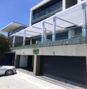 un coche aparcado frente a un edificio con garaje en GORDON's SHORE LUXURY APARTMENTS - Solar Powered en Gordonʼs Bay