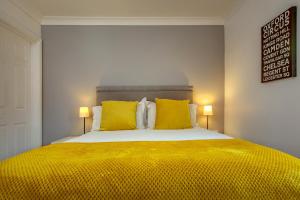 Chestnut Cottage في Felbrigg: غرفة نوم بسرير كبير مع مخدات صفراء