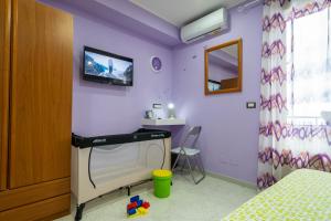 um quarto com paredes roxas e uma televisão na parede em Casa Vacanze dell'Angelo em San Mauro Castelverde