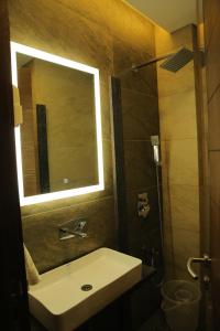 ein Bad mit einem Waschbecken, einem Spiegel und einer Dusche in der Unterkunft The Royal Grand in Karūr