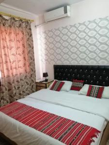 a bedroom with a large bed with a red blanket at Hamoudah Hotel in Amman