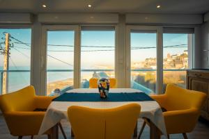 a dining room with a table and yellow chairs at La tête Ault - Une expérience unique en bord de Mer in Ault