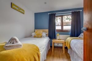2 camas en una habitación con paredes azules y ventana en Anvil & Stable Cottages, en Felbrigg