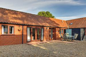 a brick house with a patio and a table at Anvil & Stable Cottages in Felbrigg