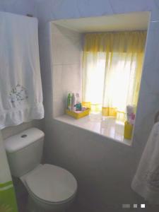 a bathroom with a white toilet and a window at El Zoela in Zamora