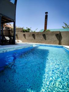 einem Pool mit blauem Wasser vor einem Gebäude in der Unterkunft UNICA Casa Centro frente al lago, pileta climatizada, 4 dorm, 3 baños, 3 autos, aire in Villa Carlos Paz