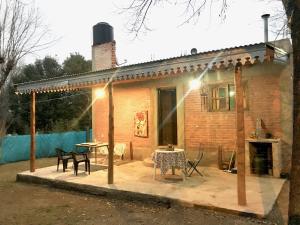 a house with a patio with a table and chairs at Pintoresca Cabaña Céntrica a pasos del río Mina Clavero in Mina Clavero