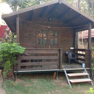 a wooden cabin with a porch and a chair at Lamarine Morjim Beach cottages in Old Goa