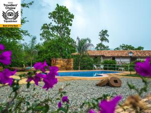 a resort with a swimming pool and purple flowers at Hotel Hacienda Macedonia in Barichara