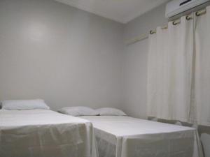 two beds with white linens in a room with a window at Pousada Aliança in Pirenópolis