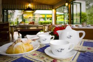 una mesa con tazas de té y una pastelería en ella en Hotel Marilù, en Eraclea Mare