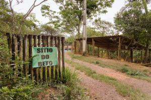 un cartel en una cerca al lado de un camino de tierra en Chalés do Beto em Macacos en Macacos