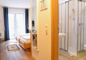 uma casa de banho com um chuveiro, um lavatório e um espelho. em Waldhotel Twiehaus Garni em Lübeck