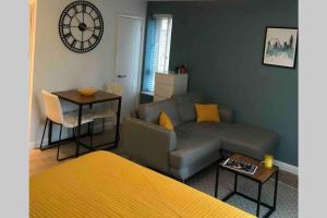 a living room with a couch and a clock on the wall at Alison15 - Superior Clifton Studio Apartment in Bristol