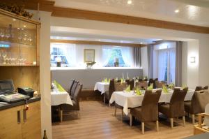 uma sala de jantar com mesas e cadeiras brancas em Waldhotel Twiehaus Garni em Lübeck