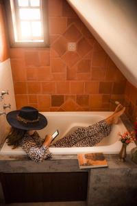 a woman laying in a bath tub with a hat at Casa da Estacao - A casa mais charmosa de Morretes! in Morretes