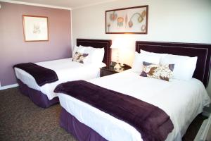 two beds in a hotel room with white and purple at Quail Park Lodge in Kanab