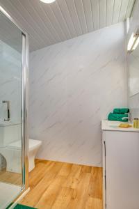 La salle de bains est pourvue de murs blancs et de parquet. dans l'établissement The Covey, à Felbrigg