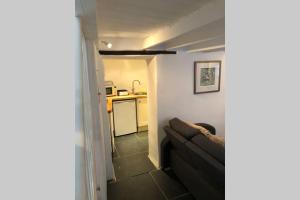 a living room with a couch and a kitchen at Molls Yard Traditional Cottage in Port Isaac