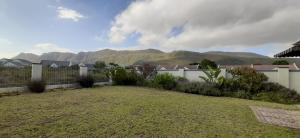a backyard with a fence and mountains in the background at Hadingham Russell Holiday House in Hermanus