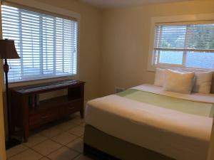 a bedroom with a bed and a desk and two windows at Pacific Reef Hotel & Light Show in Gold Beach