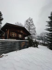 uma cabana de madeira na neve com uma cerca em Berghütte Wattenberg em Wattenberg
