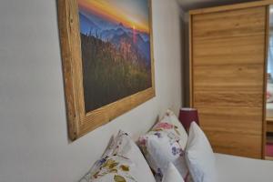 ein Gemälde an der Wand über einem Bett mit Kissen in der Unterkunft Ferienwohnungen Kappeler in Bad Hindelang