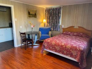 a bedroom with a bed and a table and chair at Motel Des Erables in Coteau-du-Lac +22 photos