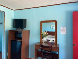 a room with a mirror and a desk with a television at Motel Des Erables in Coteau-du-Lac
