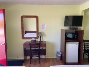 a room with a desk with a mirror and a tv at Motel Des Erables in Coteau-du-Lac